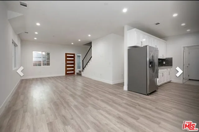 a view of a kitchen with refrigerator and wooden floor