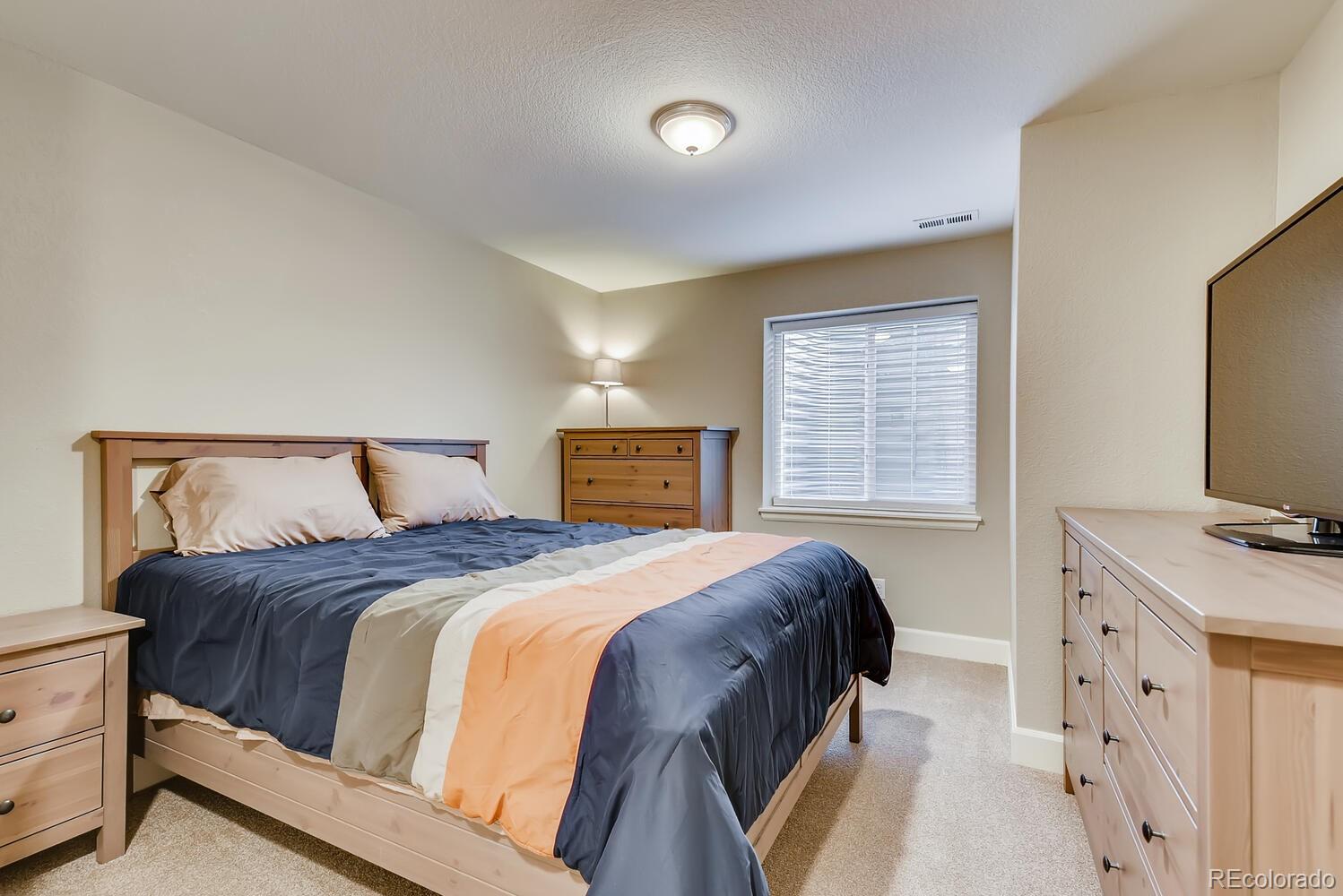 8413 Raspberry Drive Frederick, CO 80504 - Photo 20 of 27 a bedroom with a bed and a flat tv screen on dresser