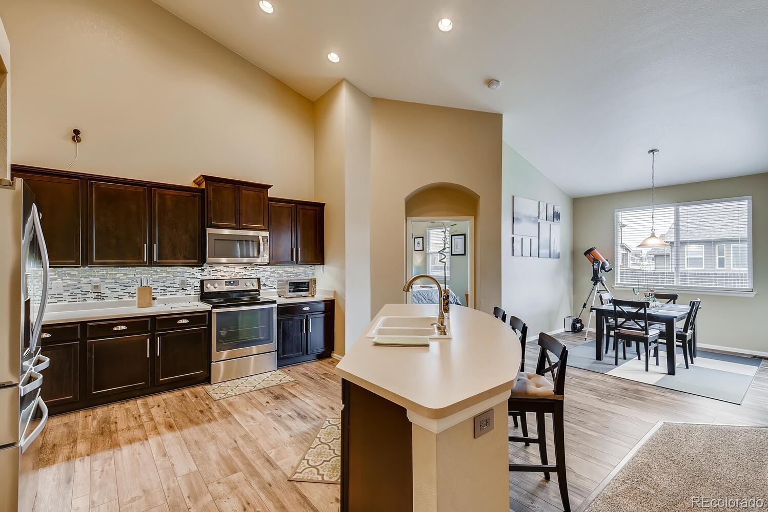 8413 Raspberry Drive Frederick, CO 80504 - Photo 7 of 27 a kitchen with stainless steel appliances a stove a sink a microwave a dining table and chairs