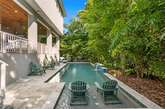 a view of a house with pool and chairs next to a yard