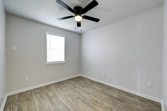 an empty room with a window and a fan