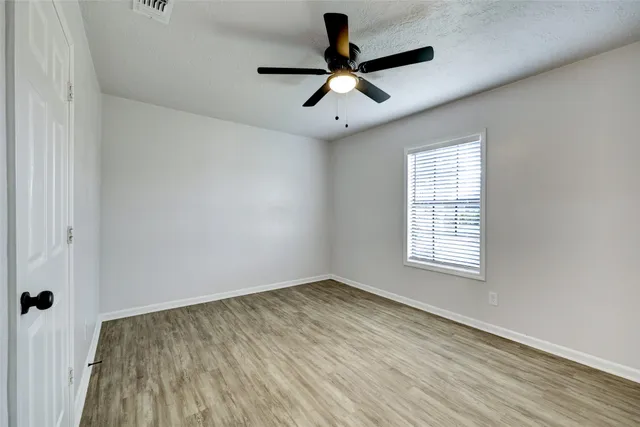 an empty room with a window and a ceiling fan