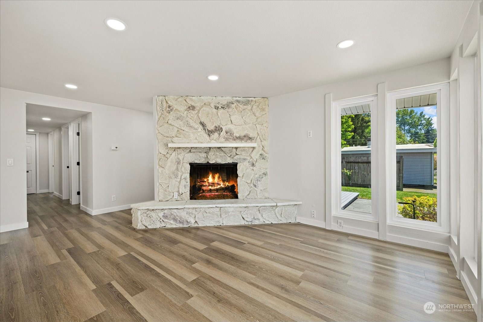 16820 120th Avenue Southeast Renton, WA 98058 - Photo 26 of 31 an empty room with wooden floor a fireplace a ceiling fan and windows