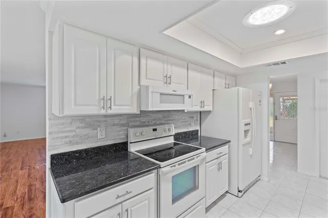 a kitchen with white cabinets and white appliances