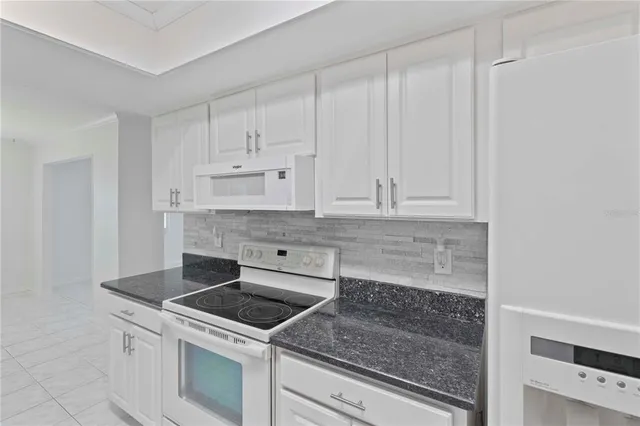 a kitchen with granite countertop white cabinets and white stainless steel appliances