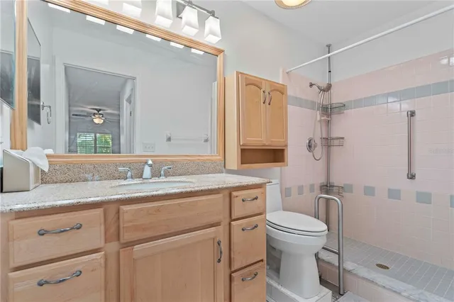 a bathroom with a granite countertop sink toilet a mirror a vanity and shower