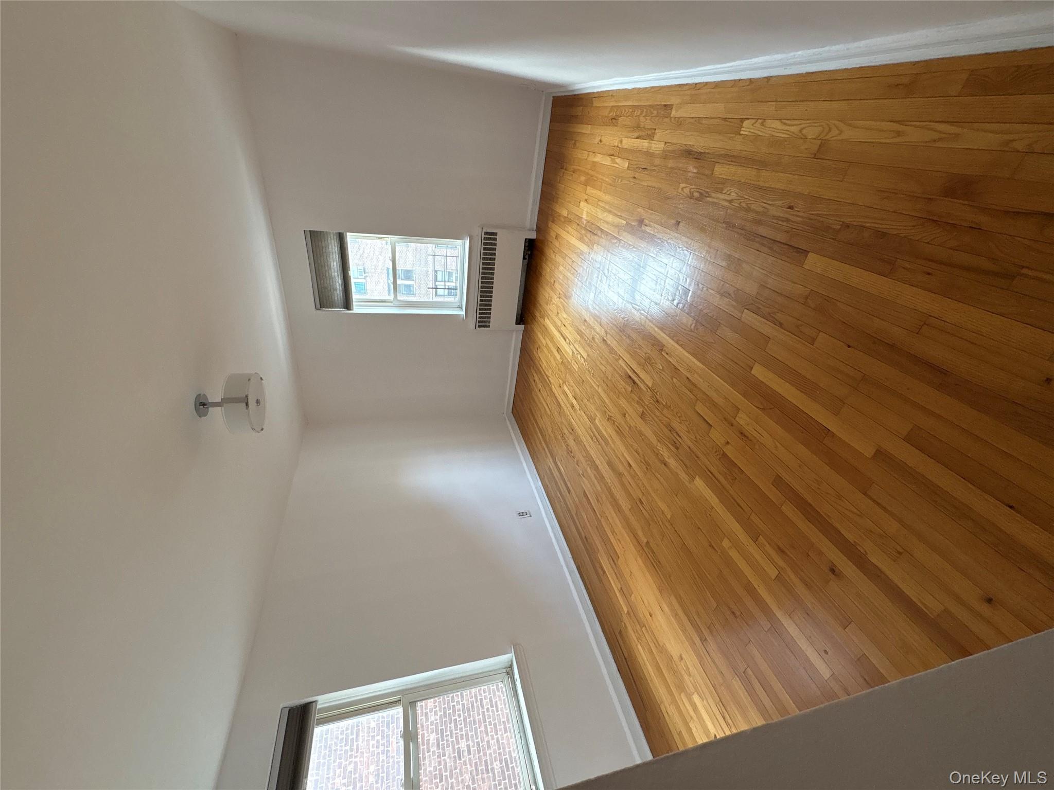 2090 Barnes Avenue, Unit 4D Bronx, NY 10462 - Photo 9 of 14 an empty room with wooden floor and windows