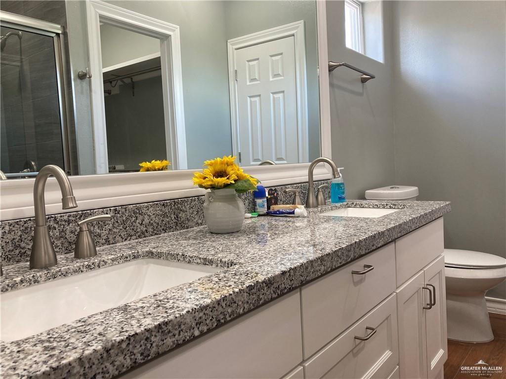 2103 South 6th Street McAllen, TX 78503 - Photo 11 of 33 Bathroom with a spacious closet, a stall shower, double vanity, and dark wood-style floors