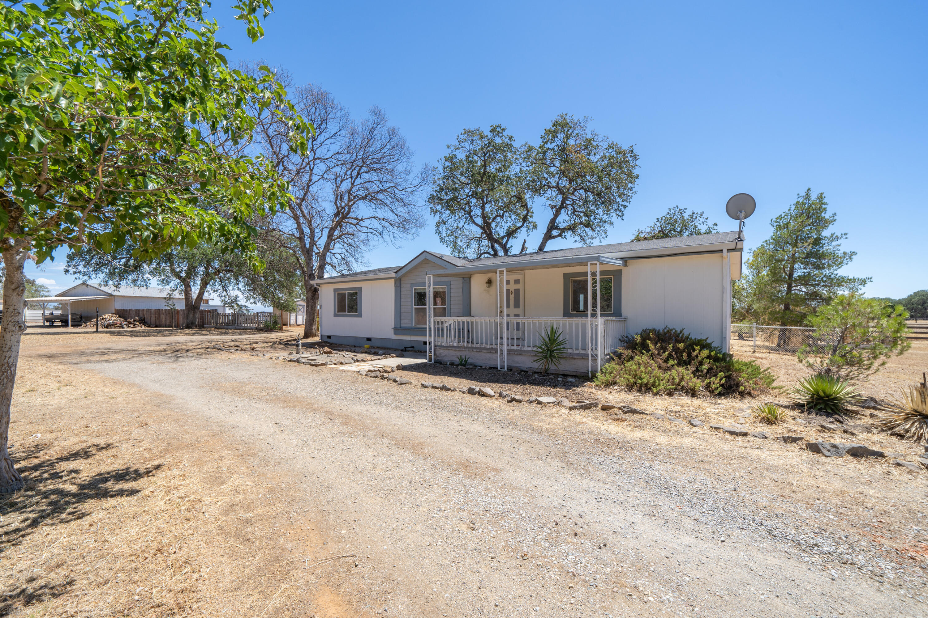 19035 Ridge Road Red Bluff, CA 96080 - Photo 1 of 74 a front view of a house with a dirt yard and a large tree