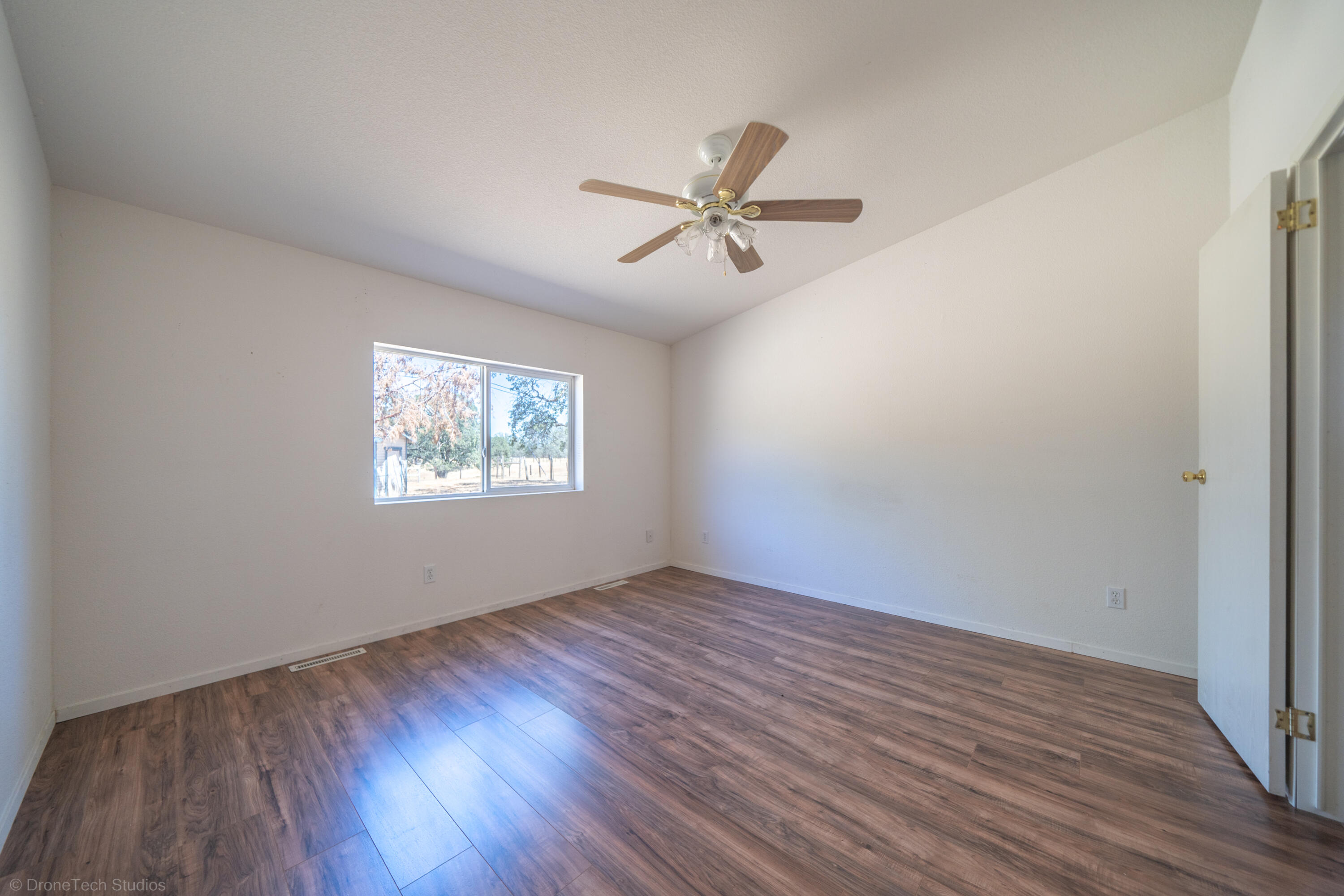 19035 Ridge Road Red Bluff, CA 96080 - Photo 26 of 74 an empty room with wooden floor ceiling fan and windows