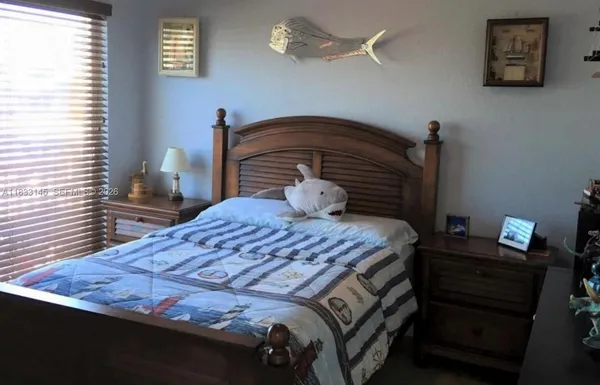 a bedroom with a bed and a lamp on the dresser