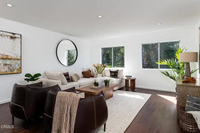 a living room with furniture a window and a potted plant