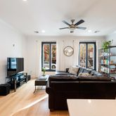 a living room with couches a flat tv screen and a dining table with wooden floor