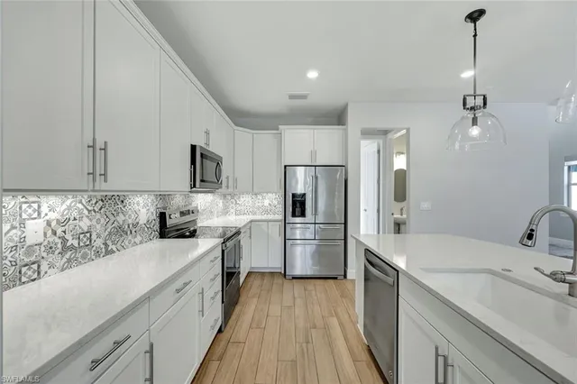a kitchen with a sink a counter top space stainless steel appliances and cabinets