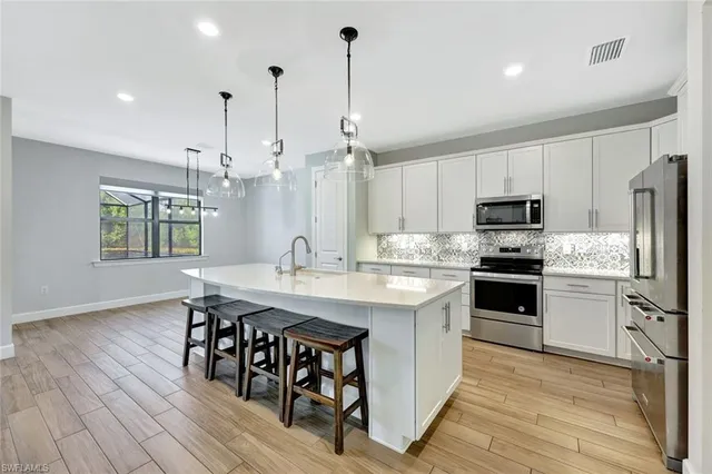 a kitchen with stainless steel appliances granite countertop a sink a stove a refrigerator and island with wooden floor