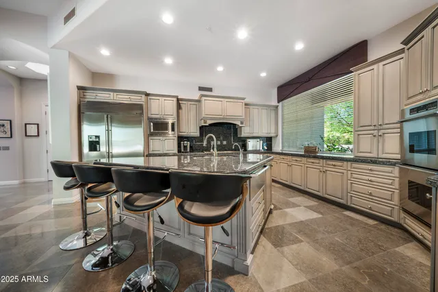 a kitchen with granite countertop a stove a sink a dining table and chairs