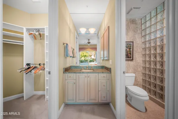 a bathroom with a granite countertop toilet a sink and a mirror