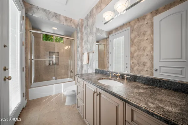 a bathroom with a granite countertop sink a toilet a mirror and shower