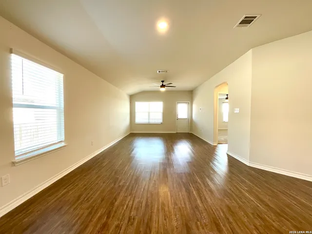 a view of empty room with wooden floor and fan