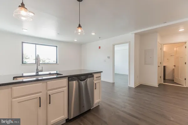 a kitchen with a sink chandelier and wooden floor