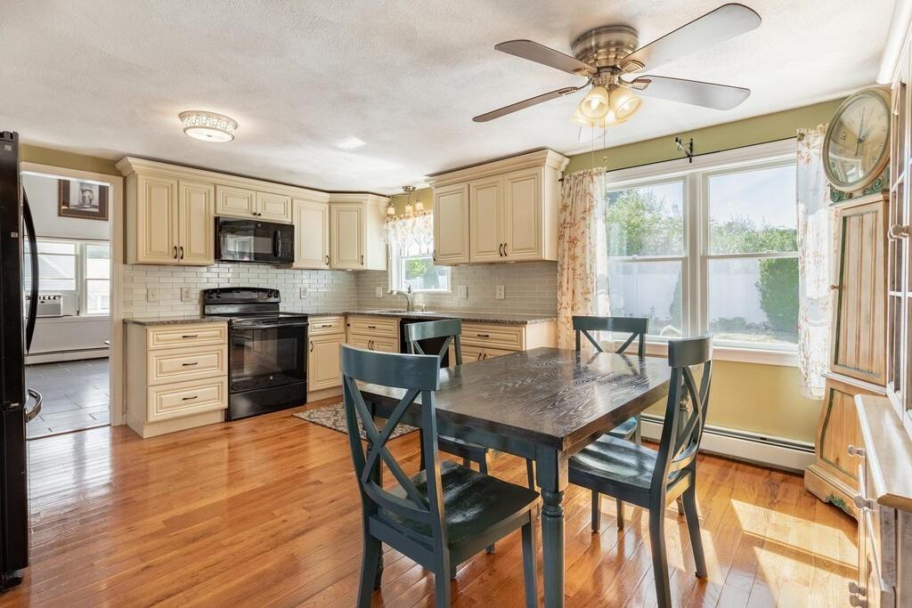 10 John Road Peabody, MA 01960 - Photo 11 of 35 a kitchen with stainless steel appliances granite countertop a stove a refrigerator a microwave a sink a dining table and chairs with wooden floor