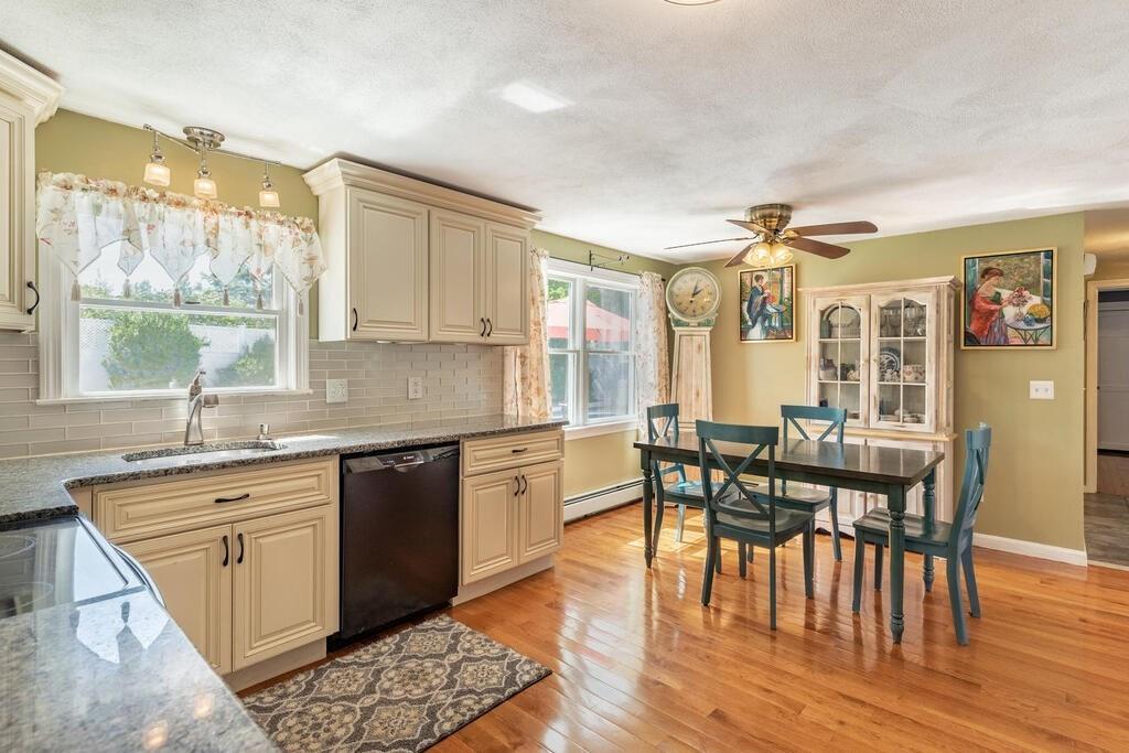 10 John Road Peabody, MA 01960 - Photo 12 of 35 a kitchen with granite countertop a stove a sink a dining table and chairs with wooden floor