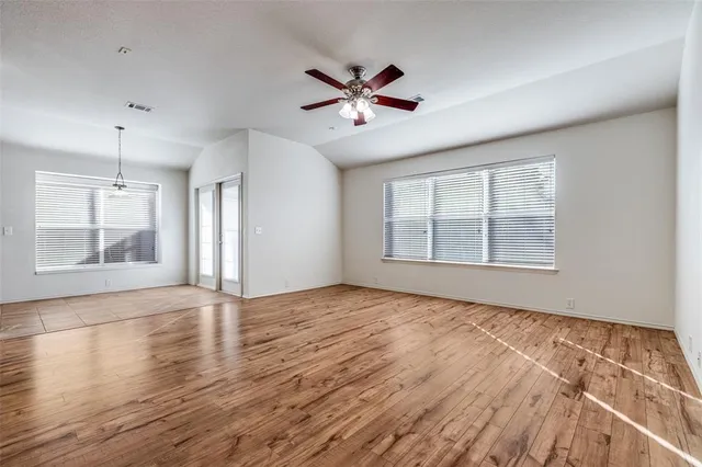 a view of an empty room with a window and wooden floor