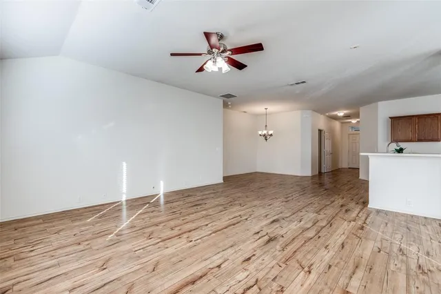 a view of empty room with wooden floor and ceiling fan