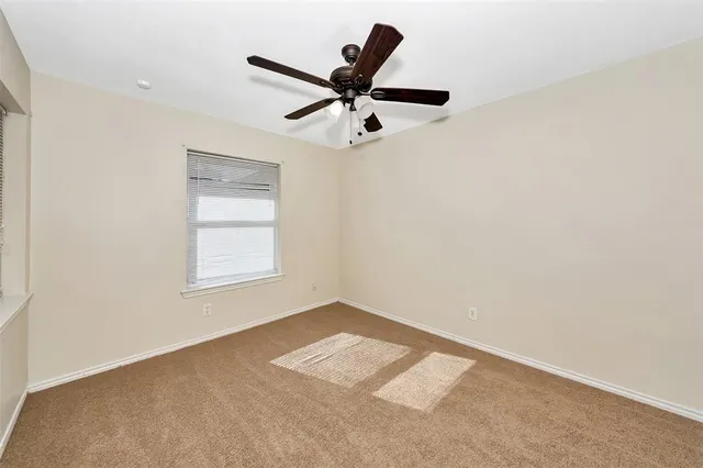 an empty room with a window and a ceiling fan