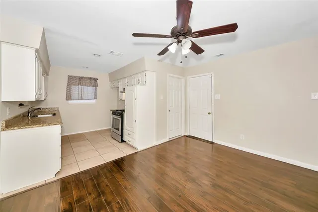 a view of a kitchen with a sink cabinet a ceiling fan and hardwood floor