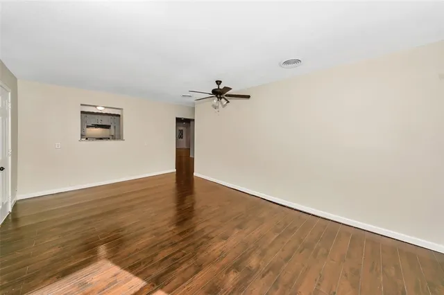 a view of empty room with wooden floor and fan