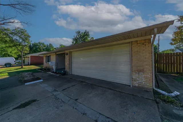 a backyard of a house with plants and large tree