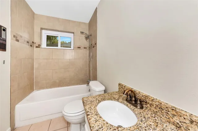 a bathroom with a granite countertop toilet a sink and a bathtub