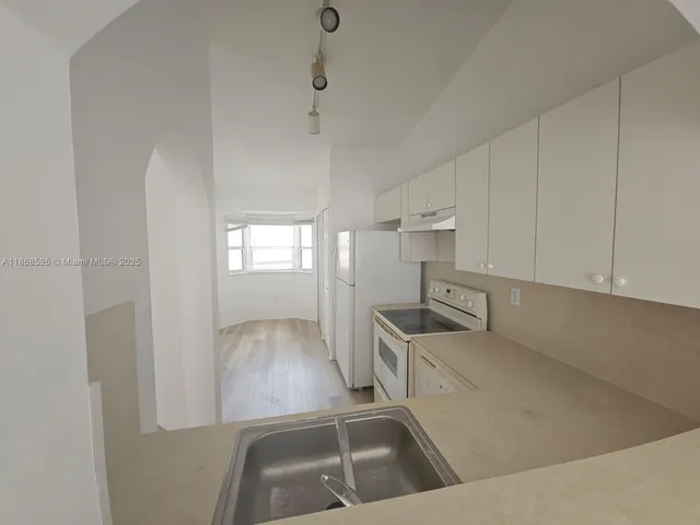 a kitchen with granite countertop a sink a stove and refrigerator
