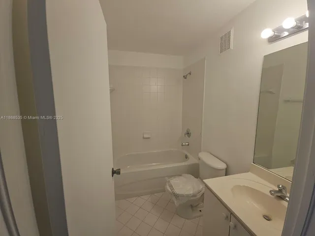 a white toilet sitting next to a bathroom sink and vanity