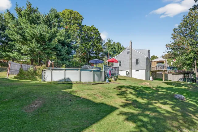 a white house with a big yard and trees with wooden fence