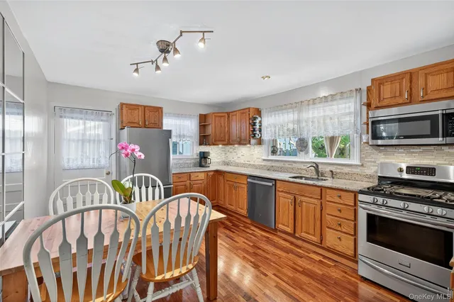 a kitchen with stainless steel appliances granite countertop a stove a sink dishwasher a dining table and chairs with wooden floor