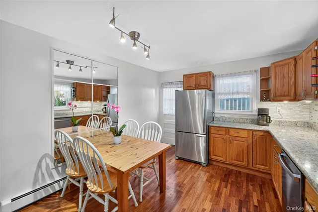 a kitchen with stainless steel appliances granite countertop a refrigerator a stove a sink dishwasher a dining table and chairs with wooden floor