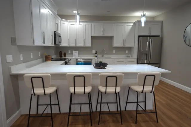 a kitchen with stainless steel appliances granite countertop a table chairs refrigerator and sink