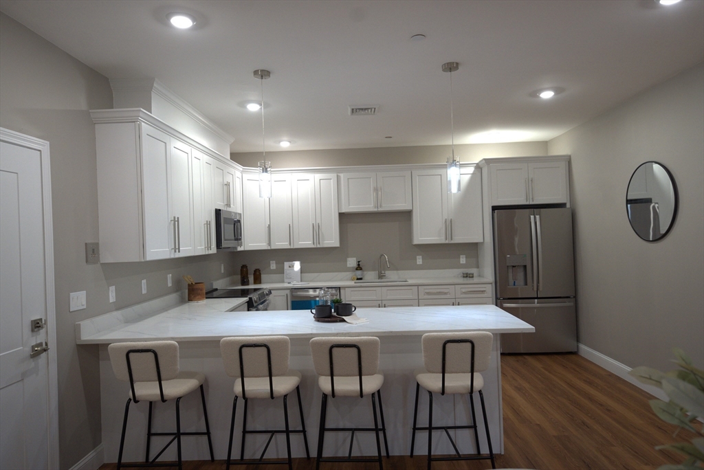 13 Nahant Street, Unit 4B Lynn, MA 01902 - Photo 4 of 28 a kitchen with a table chairs refrigerator and microwave