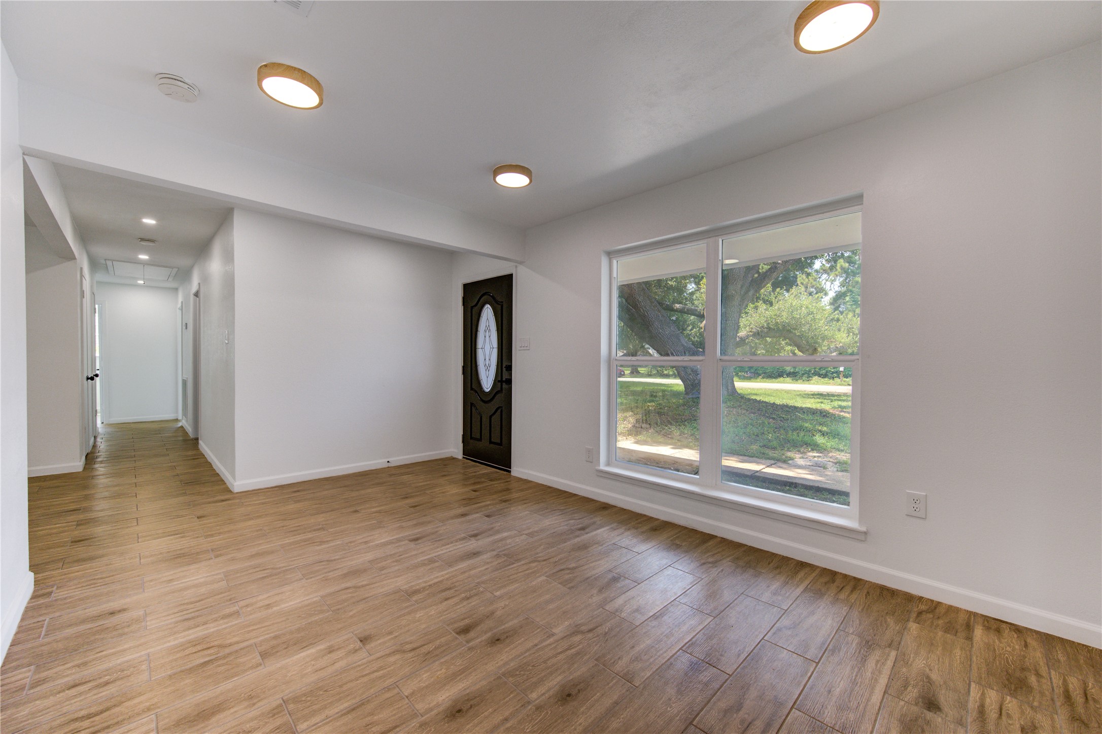 5411 Logston Lane Spring, TX 77389 - Photo 8 of 50 Bright and inviting entryway featuring wood-look flooring, a large window with serene outdoor views, and modern recessed lighting.