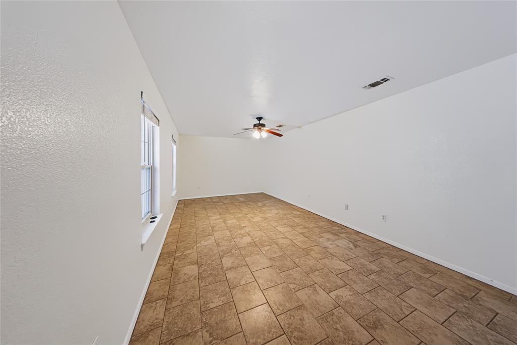 560 Green Acres Road Weatherford, TX 76088 - Photo 31 of 35 Spacious room featuring tile flooring, neutral wall tones, multiple windows, and a ceiling fan