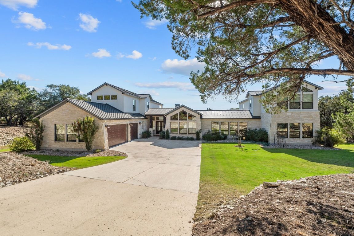 20607 Thurman Bend Road Spicewood, TX 78669 - Photo 1 of 40 View of front of house with concrete driveway, a standing seam roof, stone siding, a metal roof, and a front yard