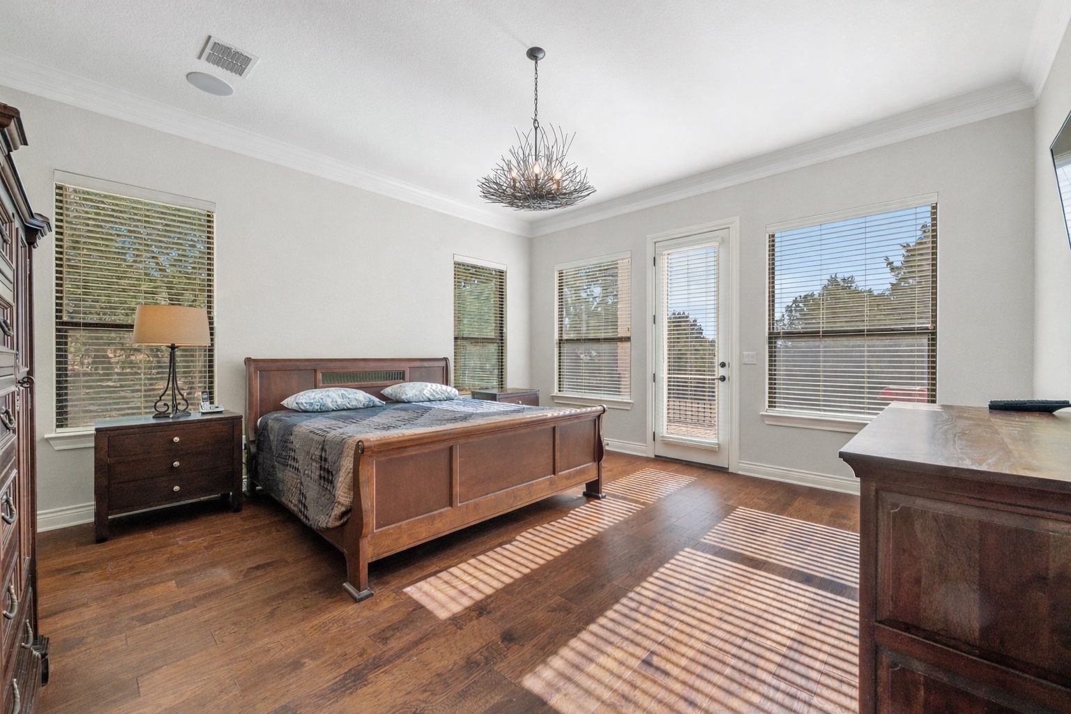 20607 Thurman Bend Road Spicewood, TX 78669 - Photo 13 of 39 a spacious bedroom with a bed a chandelier and a window
