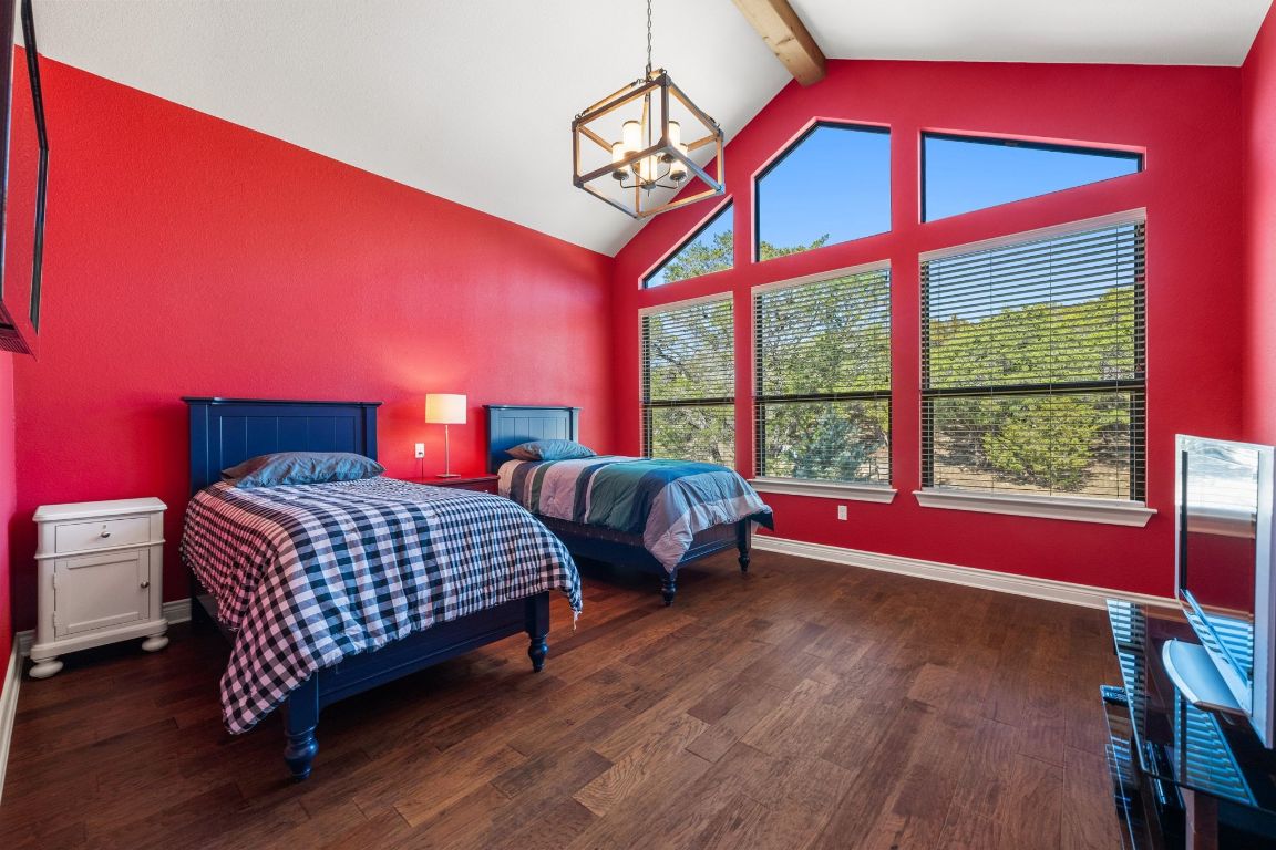 20607 Thurman Bend Road Spicewood, TX 78669 - Photo 21 of 40 Bedroom with beamed ceiling, dark wood-style flooring, high vaulted ceiling, and a chandelier