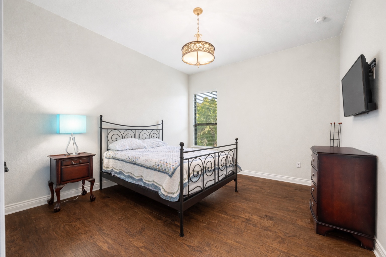 20607 Thurman Bend Road Spicewood, TX 78669 - Photo 21 of 39 a bedroom with a bed a flat screen tv and a chandelier