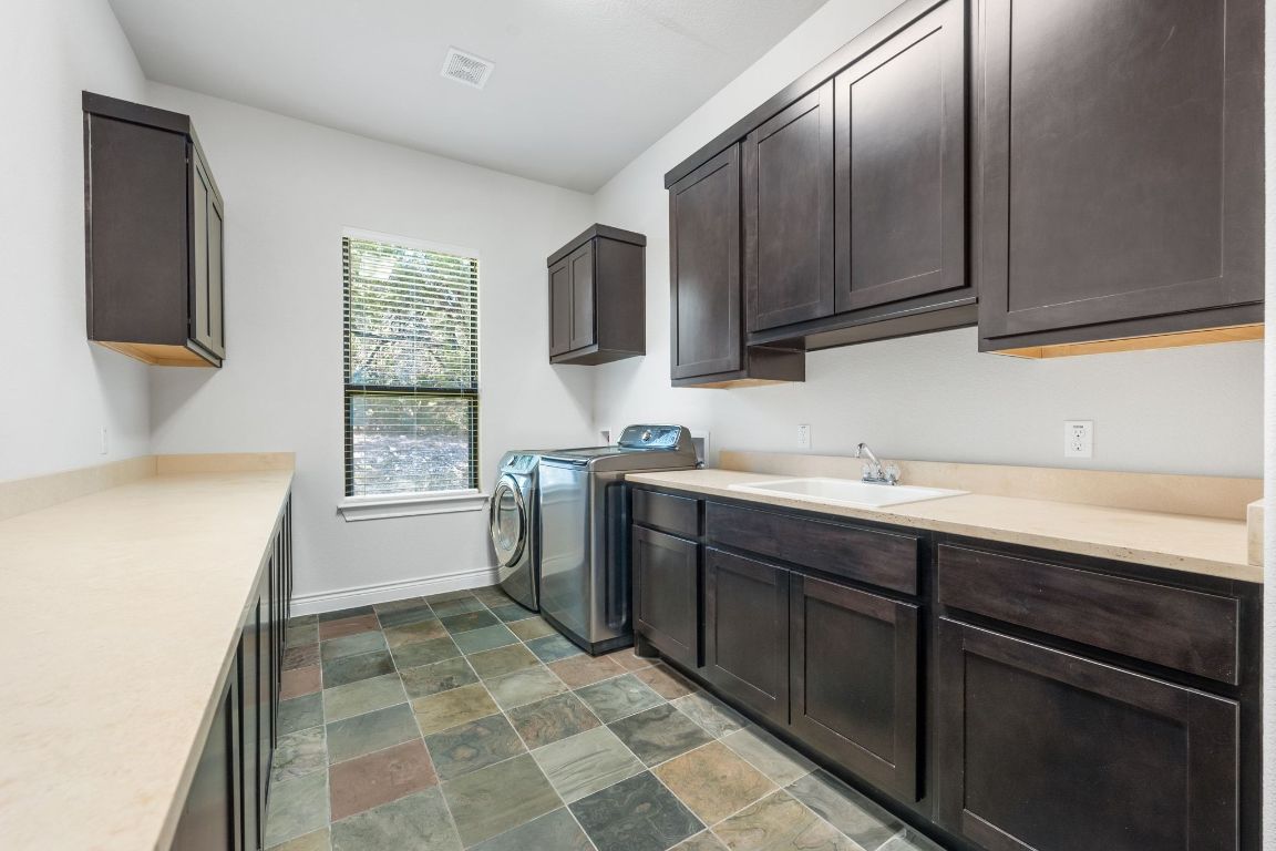 20607 Thurman Bend Road Spicewood, TX 78669 - Photo 25 of 40 Laundry room featuring stone finish floors, separate washer and dryer, and cabinet space