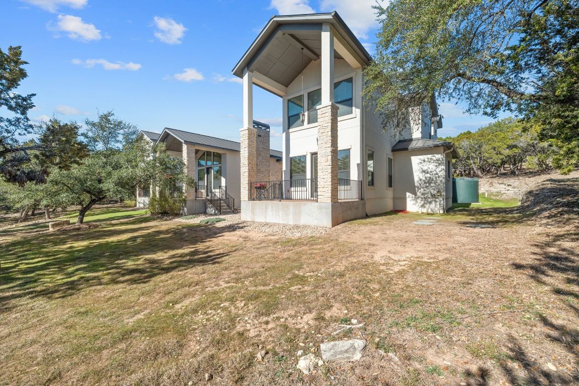 20607 Thurman Bend Road Spicewood, TX 78669 - Photo 27 of 40 Rear view of property with a balcony, stucco siding, and a yard