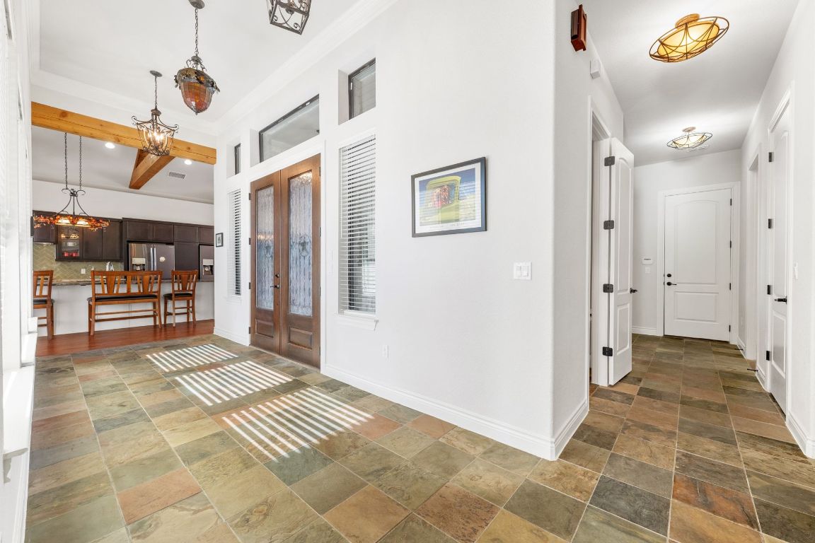 20607 Thurman Bend Road Spicewood, TX 78669 - Photo 3 of 40 Foyer entrance with french doors, stone tile flooring, a chandelier, and beamed ceiling