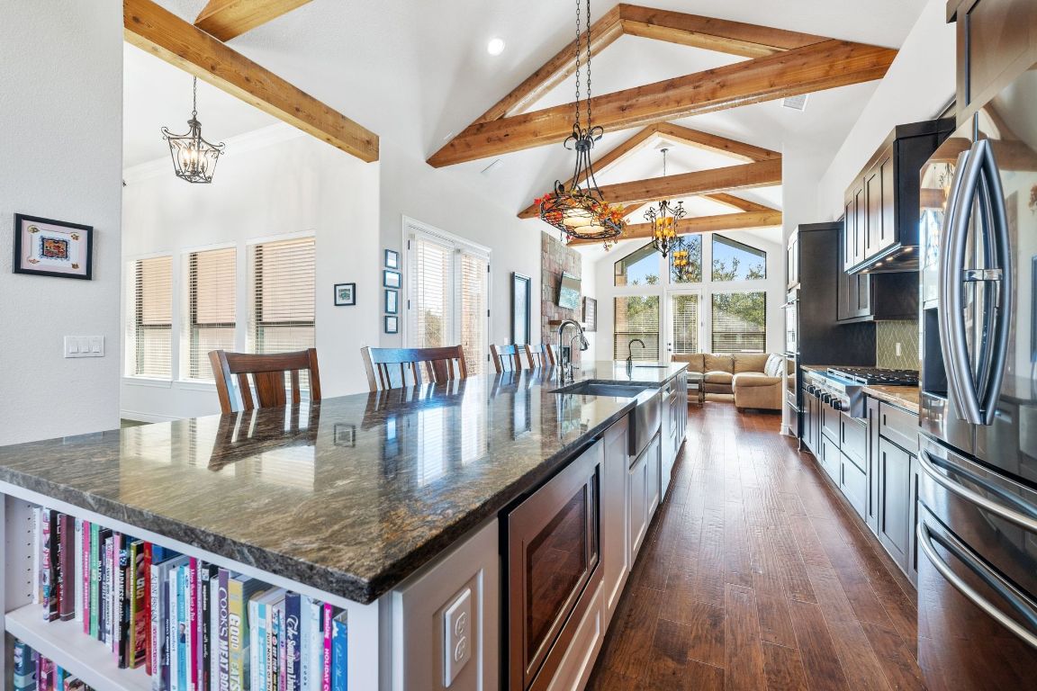 20607 Thurman Bend Road Spicewood, TX 78669 - Photo 5 of 40 Kitchen featuring a chandelier, a spacious island, high vaulted ceiling, dark stone counters, and appliances with stainless steel finishes